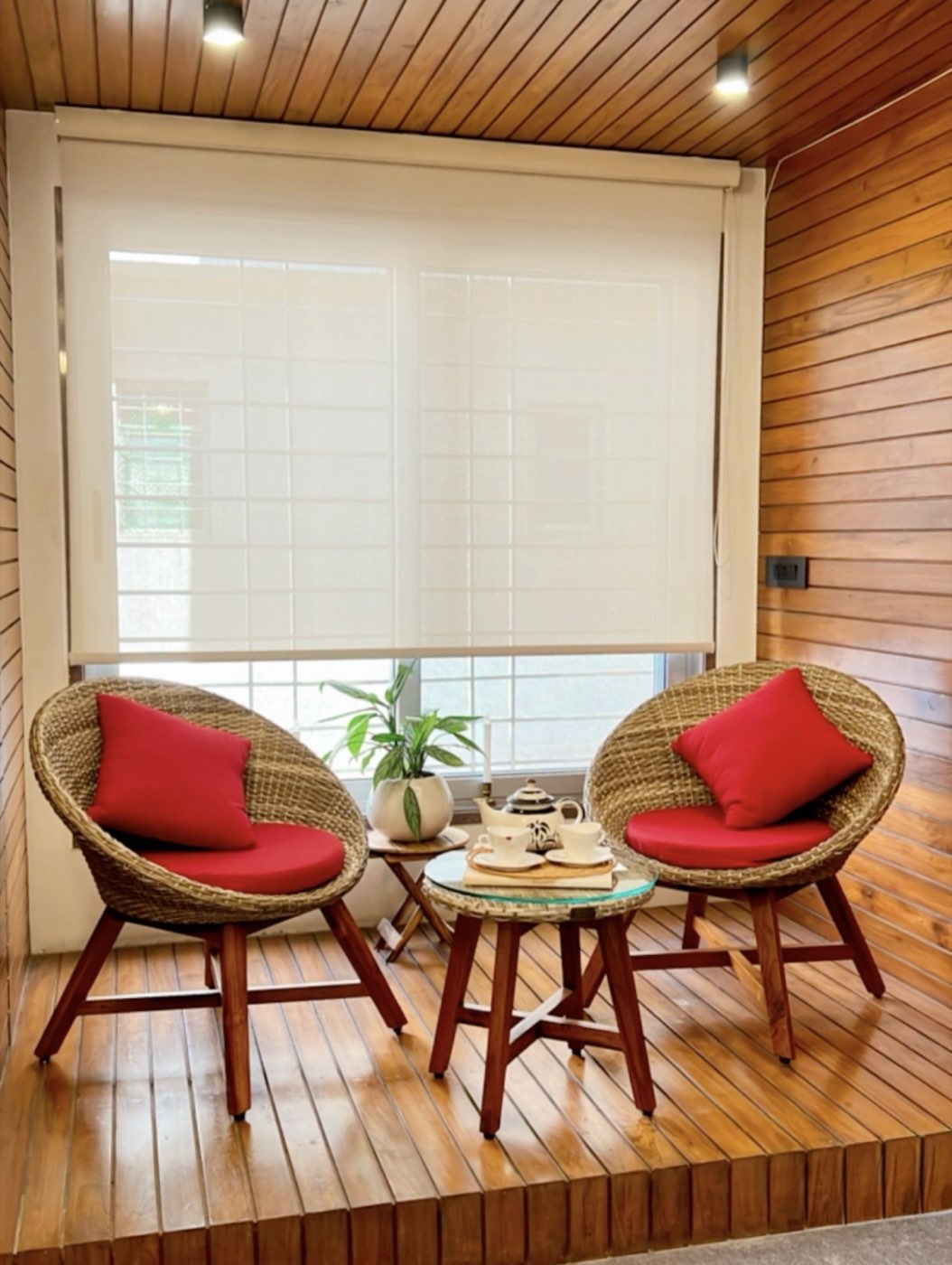 Balcony seating nook with woven chairs and red cushions